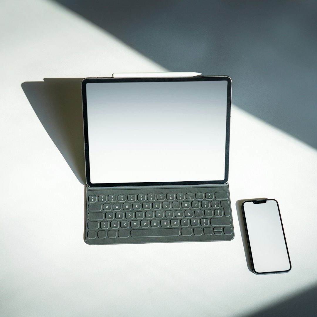 Ein Tablet mit Tastatur und ein Smartphone, beide auf einem Tisch in sanftem Licht. Pflegekoordination Einsatzgebiet Berlin Brandenburg